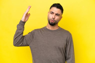 Genç Arap yakışıklı adam sarı arka planda izole edilmiş, yorgun ve hasta bir ifadeyle.