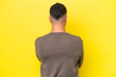 Young Arab handsome man isolated on yellow background in back position