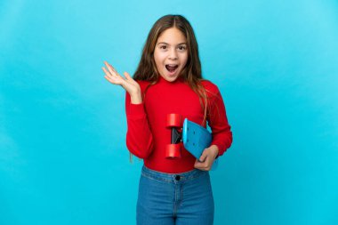 Küçük kız mavi arka planda kayıyor ve sürpriz jest yapıyor.