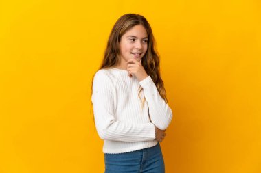 İzole edilmiş sarı arka plan üzerinde çocuk yana bakıyor ve gülümsüyor