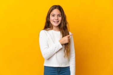 İzole edilmiş sarı arka plan üzerinde çocuk bir ürün sunmak için kenarı işaret ediyor