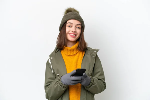 身穿白色背景隔离冬季夹克的乌克兰年轻女子用手机传达了一条信息 — 图库照片