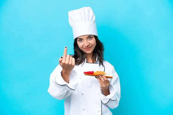 Young hispanic chef woman holding sashimi isolated on blue background doing coming gesture