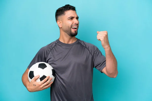 Young Arab Handsome Man Isolated Blue Background Soccer Ball Celebrating — стокове фото