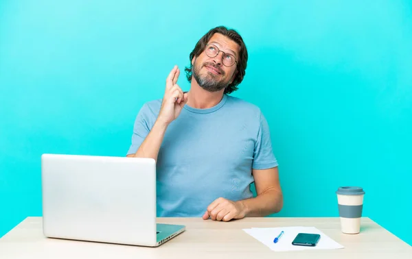 Senior Dutch Man Table Laptop Isolated Blue Background Fingers Crossing — Stock Photo, Image