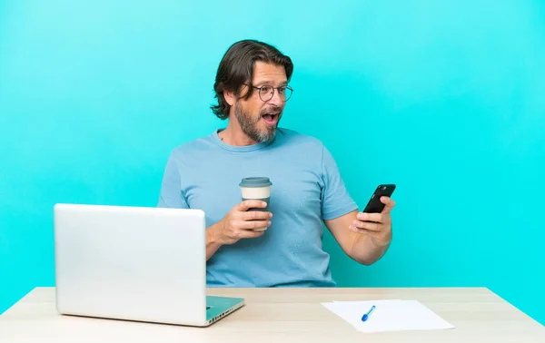 Homem Holandês Sênior Uma Mesa Com Laptop Isolado Fundo Azul — Fotografia de Stock