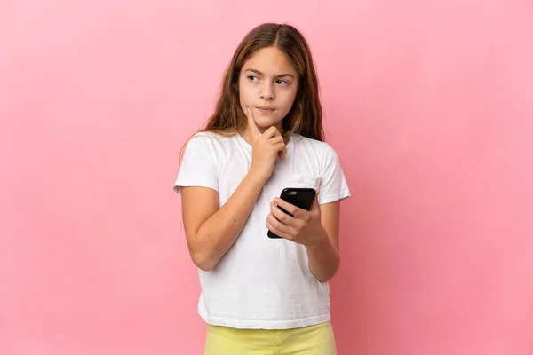Kind Geïsoleerde Roze Achtergrond Met Behulp Van Mobiele Telefoon Denken — Stockfoto