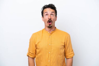 Bıyıklı genç adam beyaz arka planda izole edilmiş yukarı bakıyor ve şaşırmış bir ifadeyle