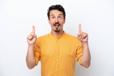 Bıyıklı genç adam beyaz arka planda izole edilmiş, şaşırmış ve yukarı bakıyor.