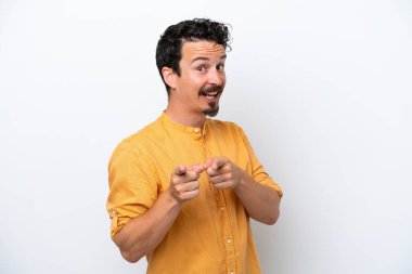 Bıyıklı genç adam beyaz arka planda izole edilmiş, şaşırmış ve ön tarafı işaret ediyor.