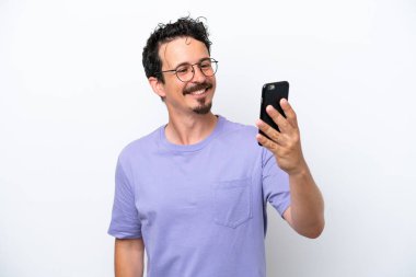 Bıyıklı genç adam beyaz arka planda izole edilmiş selfie çekiyor.