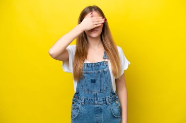 Sarı arka planda izole edilmiş genç, beyaz bir kadın elleriyle gözlerini kapatıyor. Bir şey görmek istemiyorum.