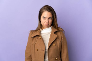 Orta yaşlı Brezilyalı kadın üzgün bir ifadeyle mor arka planda izole edilmiş.