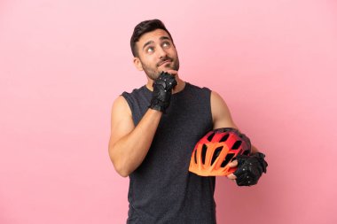 Pembe arka planda izole edilmiş genç bisikletçi yukarı bakıyor.