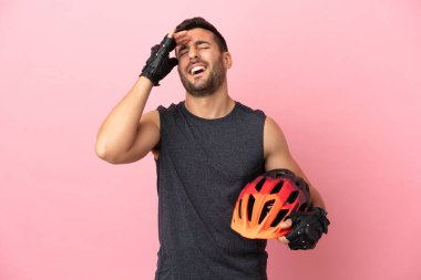 Pembe arka planda izole edilmiş genç bisikletçi çok gülümsüyor.