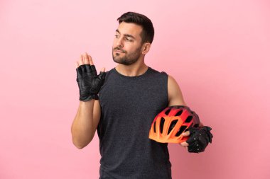 Pembe arka planda izole edilmiş genç bisikletçi dur hareketi yapıyor ve hayal kırıklığına uğruyor.