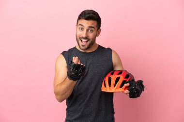 Pembe arka planda izole genç bisikletçi para hareketi yapıyor.