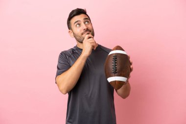 Genç, beyaz bir adam pembe arka planda izole edilmiş bir şekilde ragbi oynuyor.