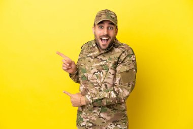 Sarı arka planda izole edilmiş asker şaşırmış ve işaret ediyor.