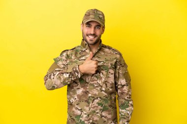 Asker sarı arka planda izole edilmiş bir şekilde baş parmak işareti yapıyor.
