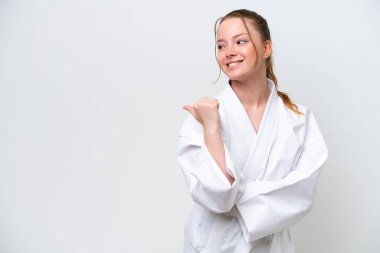 Beyaz arka planda karate yapan genç beyaz bir kız bir ürün sunmak için kenarı işaret ediyor.