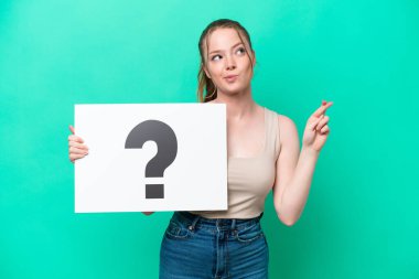 Kafkasyalı genç bir kadın yeşil arka planda izole edilmiş. Elinde üzerinde soru işareti olan bir levha var.