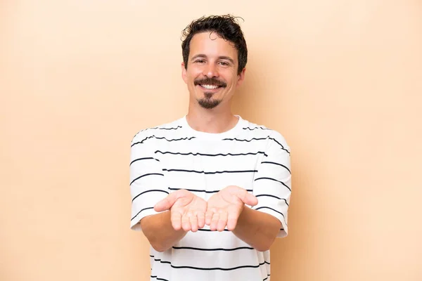 Joven Hombre Caucásico Aislado Sobre Fondo Beige Sosteniendo Espacio Copia — Foto de Stock