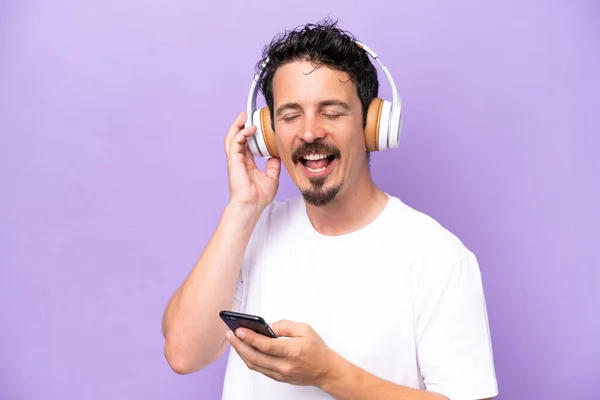 Jovem Caucasiano Isolado Fundo Roxo Ouvindo Música Com Celular Cantando — Fotografia de Stock