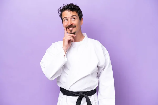 Mladý Běloch Dělá Karate Izolované Fialovém Pozadí Myšlení Nápad Zatímco — Stock fotografie