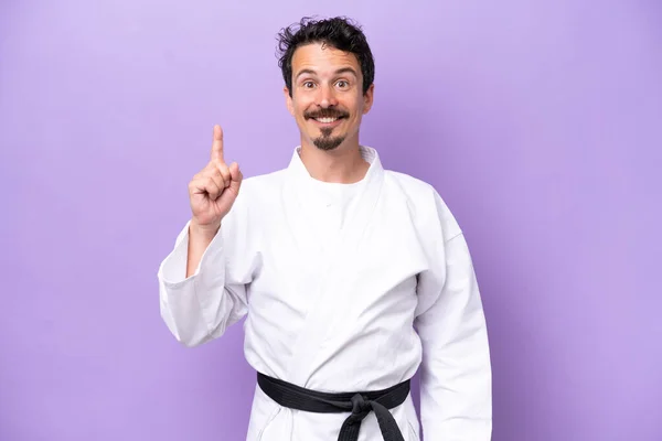 Mladý Běloch Dělá Karate Izolované Fialovém Pozadí Ukazuje Zvedá Prst — Stock fotografie