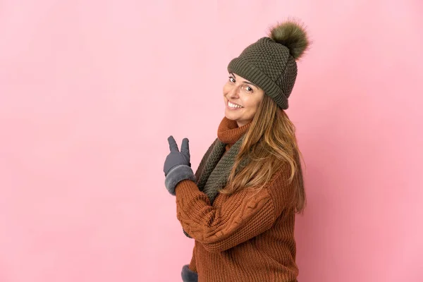 Middelbare Leeftijd Vrouw Met Winter Hoed Geïsoleerd Roze Achtergrond Wijzend — Stockfoto