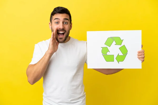 Mladý Pohledný Běloch Izolovaný Žlutém Pozadí Drží Plakát Ikonou Recyklace — Stock fotografie