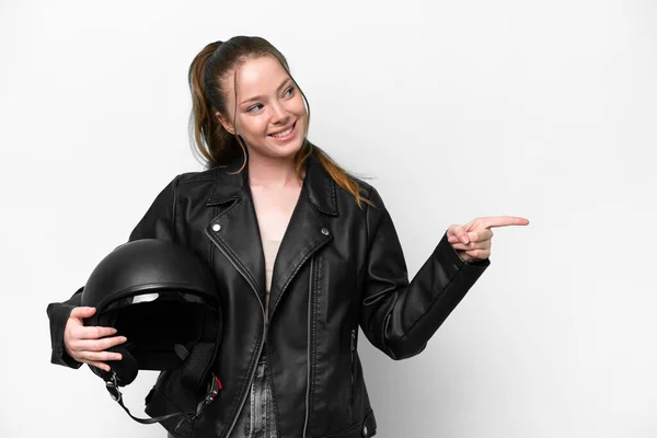 若いですCaucasian女の子とともにオートバイヘルメット隔離上の白い背景指差し指に側面と製品を提示 — ストック写真