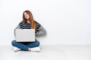 Yerde dizüstü bilgisayarlı beyaz bir kadın oturuyordu. Sırt ağrısı çekiyordu. Çabaladığı için.