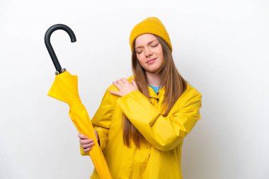 Yağmura dayanıklı ceketi ve şemsiyesi olan beyaz arka planda izole edilmiş, omuz ağrısı çeken beyaz bir kadın.