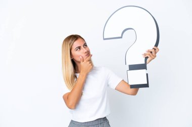 Sarışın Uruguaylı kız beyaz arka planda izole edilmiş elinde bir soru işareti simgesi var ve şüpheleri var.