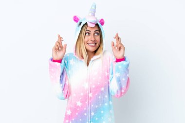 Sarışın Uruguaylı kız tek boynuzlu at pijaması giyiyor beyaz arka planda izole edilmiş ve parmakları çapraz