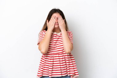 Beyaz arka planda izole edilmiş beyaz tenli genç bir kadın gözlerini elleriyle kapatıyor.