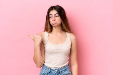 Pembe arka planda izole edilmiş genç beyaz kadın mutsuzdu ve yan tarafı gösteriyordu.