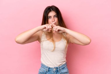 Pembe arka planda izole edilmiş beyaz bir kadın sessizlik işareti gösteriyor.