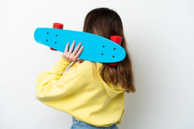 Beyaz arka planda izole edilmiş beyaz tenli genç bir kadın, arka planda kaykay yapıyor.