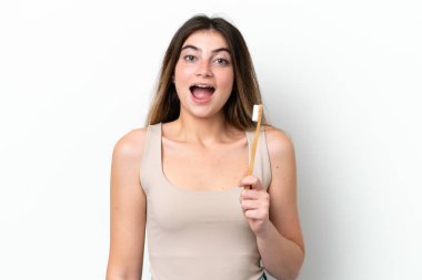 Young caucasian woman brushing teeth isolated on white background with surprise and shocked facial expression