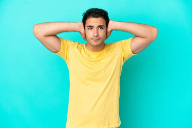 Izole mavi arka plan üzerinde Kafkas yakışıklı adam sinirli ve kulakları kapsayan