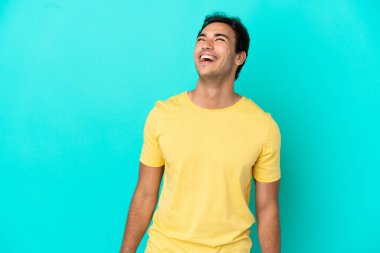 Kafkasyalı yakışıklı adam soyutlanmış mavi arka planda gülüyor.