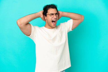 İzole edilmiş mavi arka planda beyaz, yakışıklı bir adam stresli.