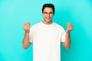 Izole mavi arka plan üzerinde Beyaz yakışıklı adam para jest yapma