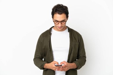 Kafkasyalı yakışıklı adam izole edilmiş beyaz arka planda cep telefonuyla mesaj gönderiyor.