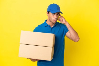 Delivery man over isolated yellow wall thinking an idea
