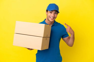 Delivery man over isolated yellow wall giving a thumbs up gesture