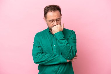 Pembe arka planda soyutlanmış orta yaşlı beyaz bir adam şüpheleri var.